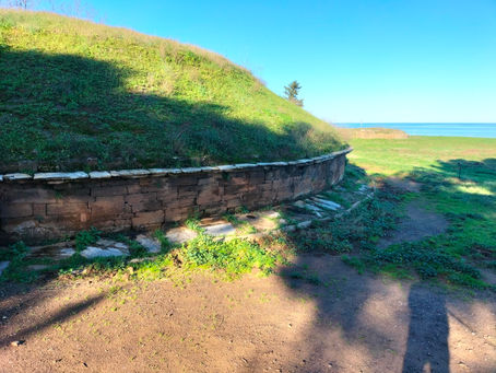 Grande tomba etrusca a tumulo nella necropoli di Populonia; in primo piano la struttura circolare e sullo sfondo il mare