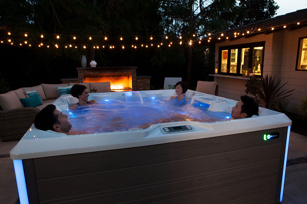 Family soaking together in a Hot Spring Highlife Collection hot tub in a backyard setting.