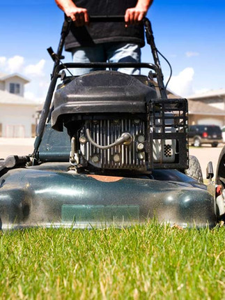 A lawn mower cutting lush, green grass on a warm, sunny summer day