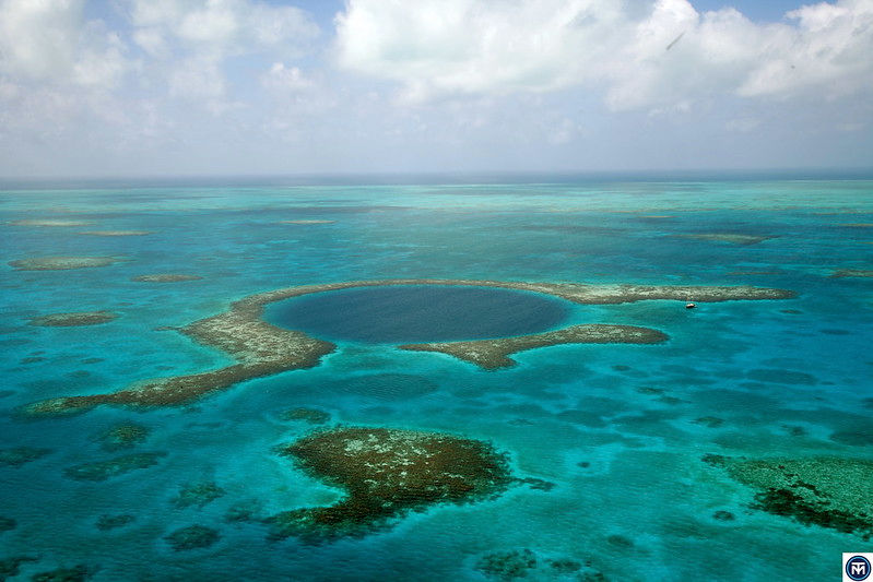 Explore the breathtaking Blue Hole in Belize—an iconic underwater sinkhole offering crystal-clear waters, vibrant marine life, and unforgettable diving experiences. The Blue Hole is located approximately 70 kilometers (about 43 miles) off the coast of Belize City. Photo: The TerraMar Project, Flickr CC BY 2.0