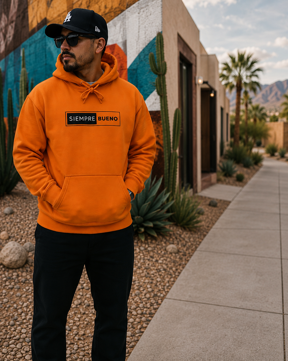 Hispanic man wearing the orange Siempre Bueno pullover hoodie in a desert-inspired setting.