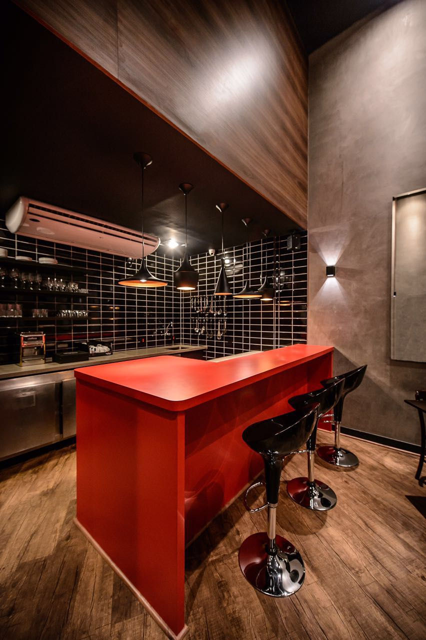 Cozinha residencial moderna com balcão vermelho e banquetas pretas.