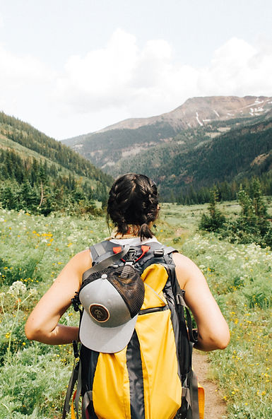 Hiker on a trail through a valley with open scenery of trees and mountains in front of them | CanStart Immigration