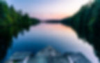 A calm and silent evening at sunset at a small forest lake in Sweden. In the foreground th