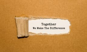 The text Together We Make The Difference appearing behind torn brown paper
