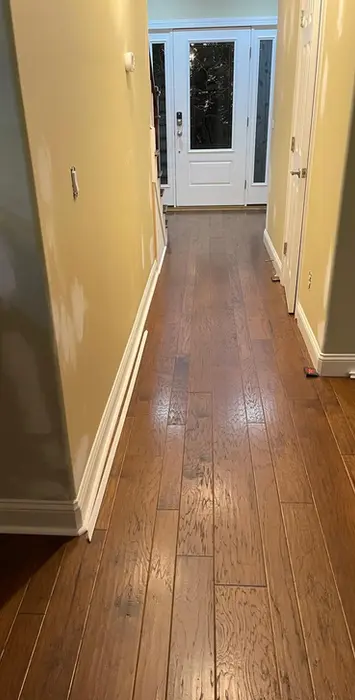 Long hallway with hardwood floors and white door