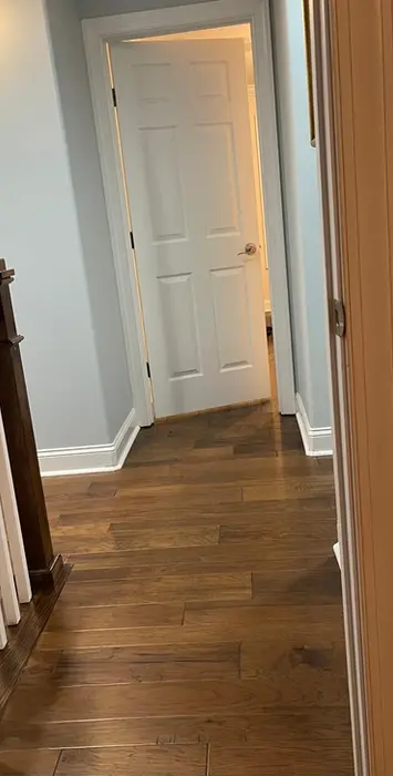 Home hallway with wood floor, staircase, and open white door