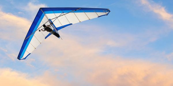 Hang glider soaring through a vibrant sunset sky