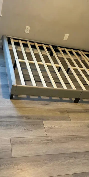 Light gray bed frame with tufted headboard on wood-look floor