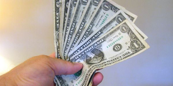 Hand holding several one-dollar bills