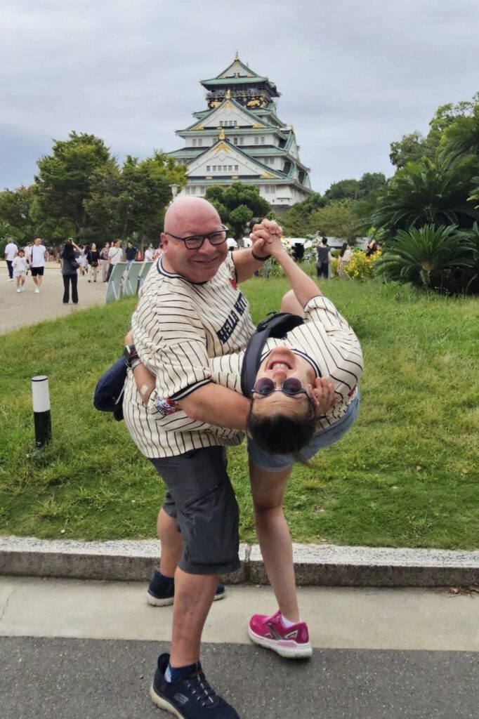 Man and woman dance happily in front of the Osaka Castle. Lucia and Glynn.
