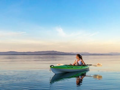 Grande étendue d'eau avec un kayak vert et une femme qui navigue