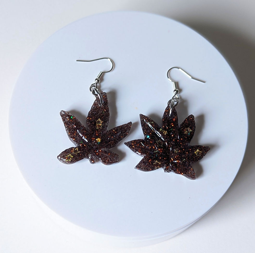 Overhead view of the Black Domina Hybrid Split Weed Leaf Earrings and their hypo-allergenic fishhook-style dangles