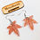 Thumbnail: Overhead view of the Medium Size Sativa leaf of the "Tangerine Dream Stoner Weed leaf Earrings"