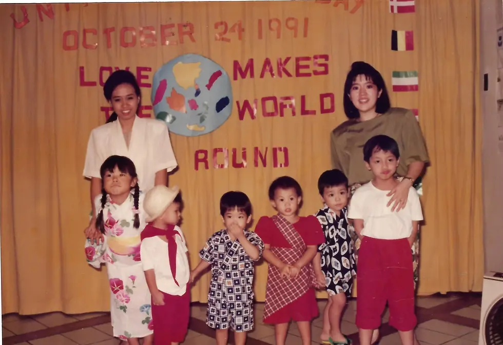 Children and adults celebrating a cultural event with colorful outfits and a backdrop of a world map.
