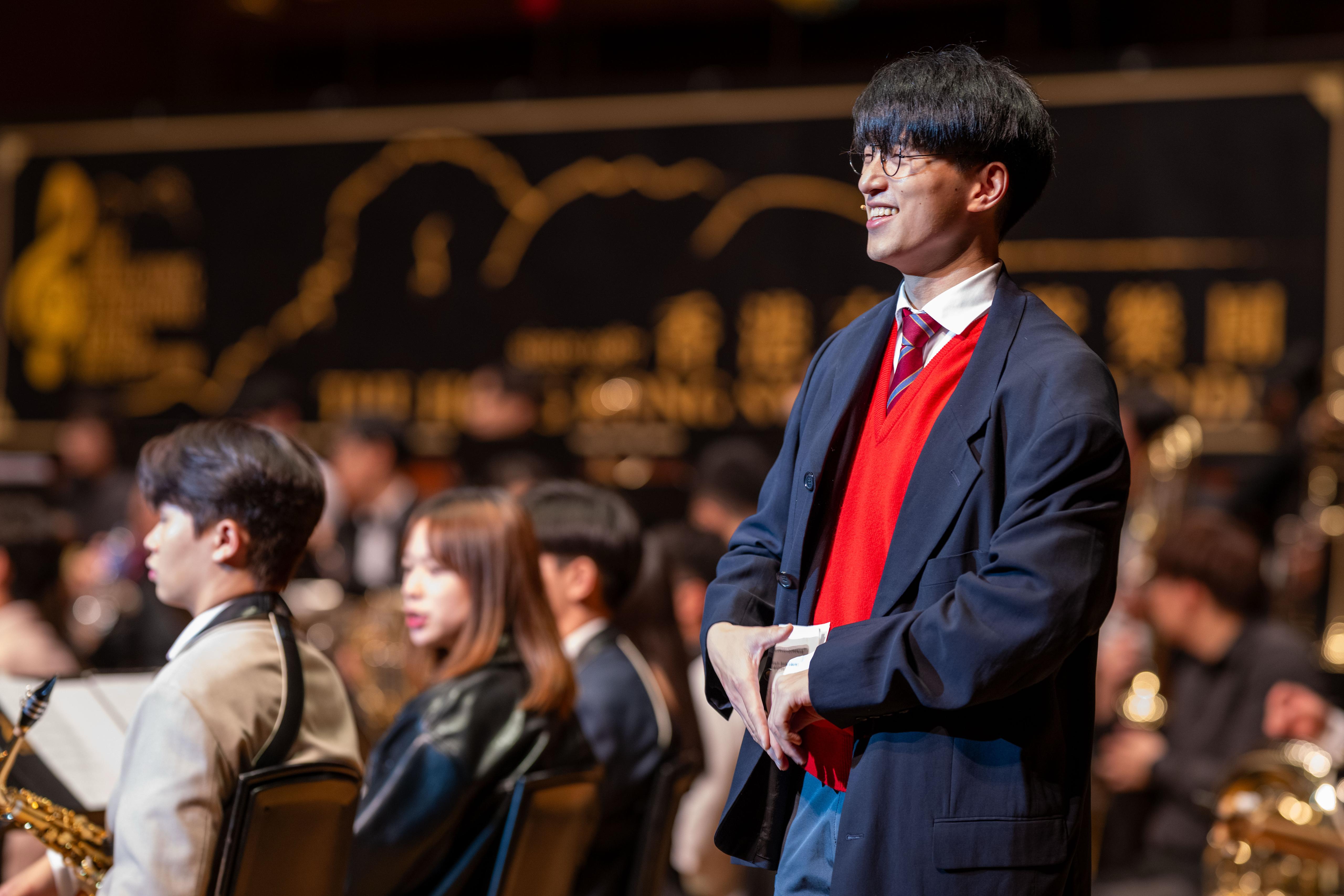 Terrence Leung performing in a red sweater and dark jacket