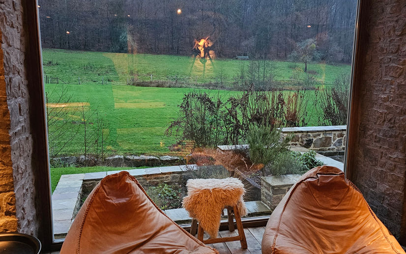 Twee zitzakken bij een groot raam met uitzicht op groen landschap.