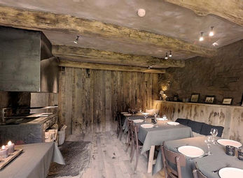 Interieur restaurant met houten balken en tafels met servies. Rustieke sfeer aanwezig.