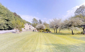 Uitgestrekt gazon en herenhuis met bomen op een zonnige dag.