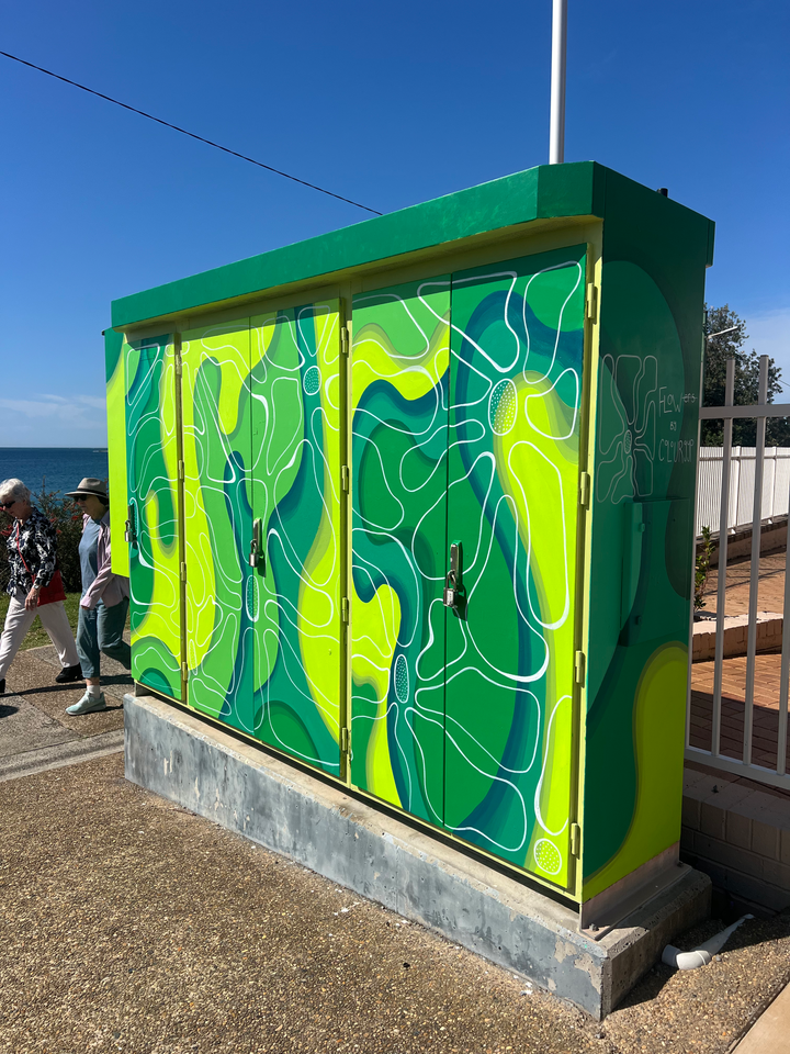 Hand-painted utility box mural in Cronulla featuring flowing green and blue linework inspired by water and topographic forms.