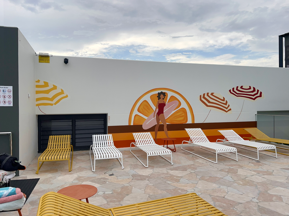 Mural of surfer and striped umbrellas near rooftop pool in Zetland.