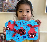 Child presenting a colorful mixed-media artwork created during a B&P art workshop