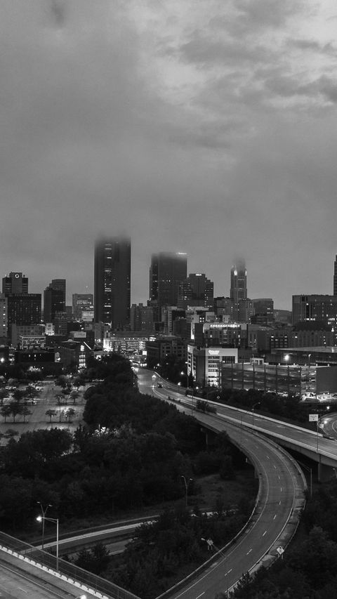 City skyline at dusk with highway traffic and cloudy evening.