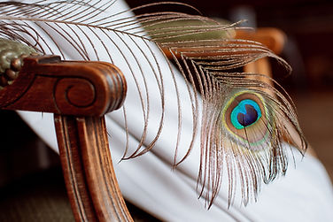 robe de mariée sur un fauteuil avec une plume de paon