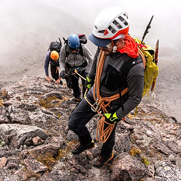 David, our lead guide, carrying technical climbing gear and a rope, leading 2 other climbers up some steep rock