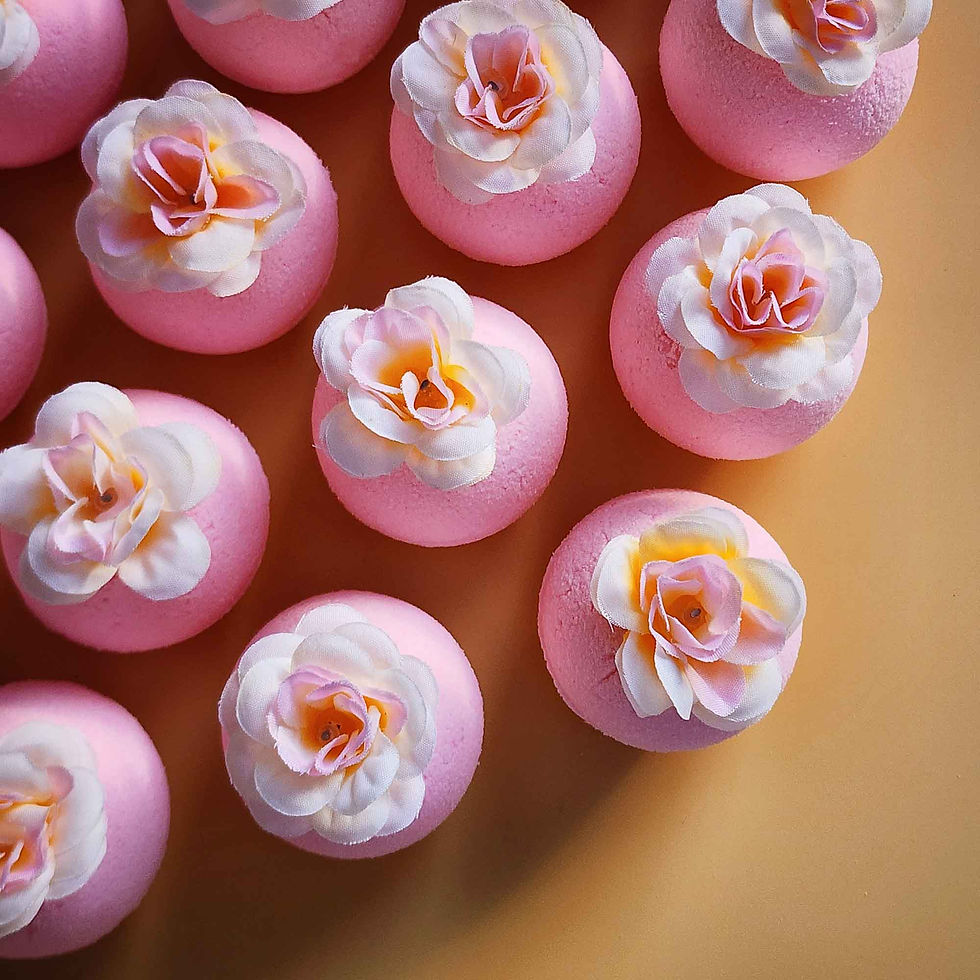 Thumbnail: Overhead view of pink magnolia bath bombs arranged together, each finished with a pale fabric flower