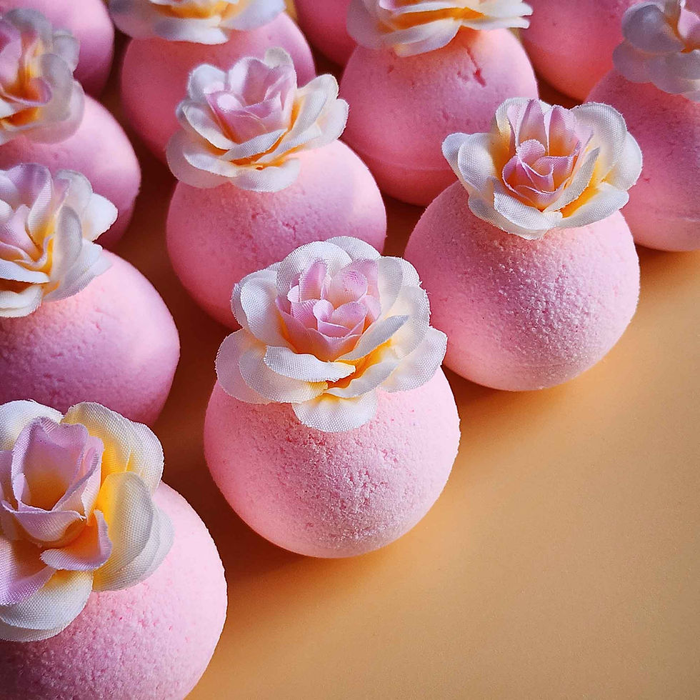 Thumbnail: Angled view of pink magnolia bath bombs with white and blush faux petals on a soft background
