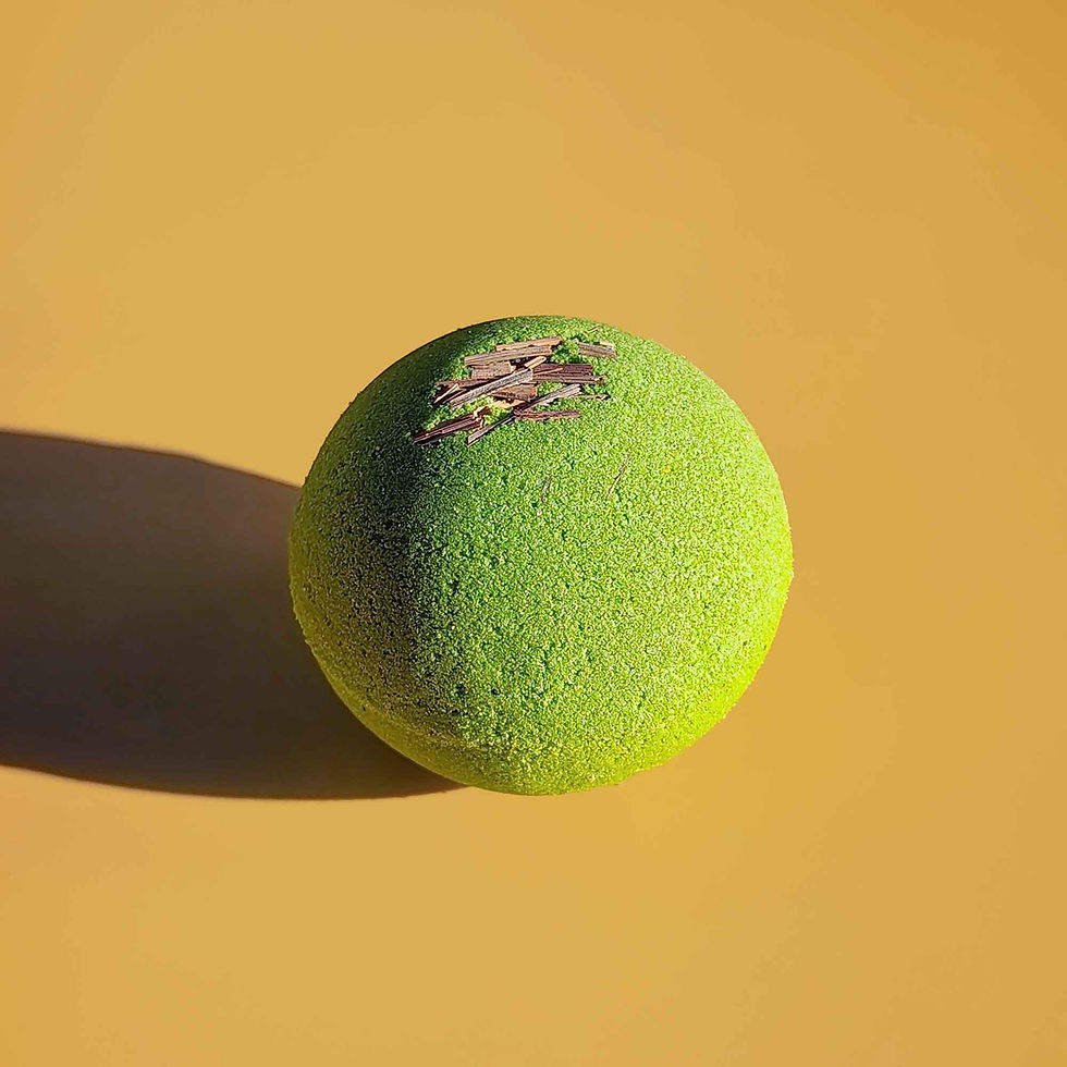 Thumbnail: Close-up of a single bright green Repair aromatherapy bath bomb with dried lemongrass on a yellow surface