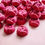 Thumbnail: rose shaped mini bath bombs coloured a deep red laid out neatly on a plain pink background