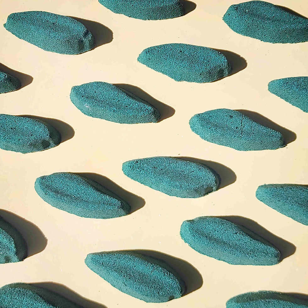 deep green long leaf shaped bath bombs laid out neatly on a plain beige background