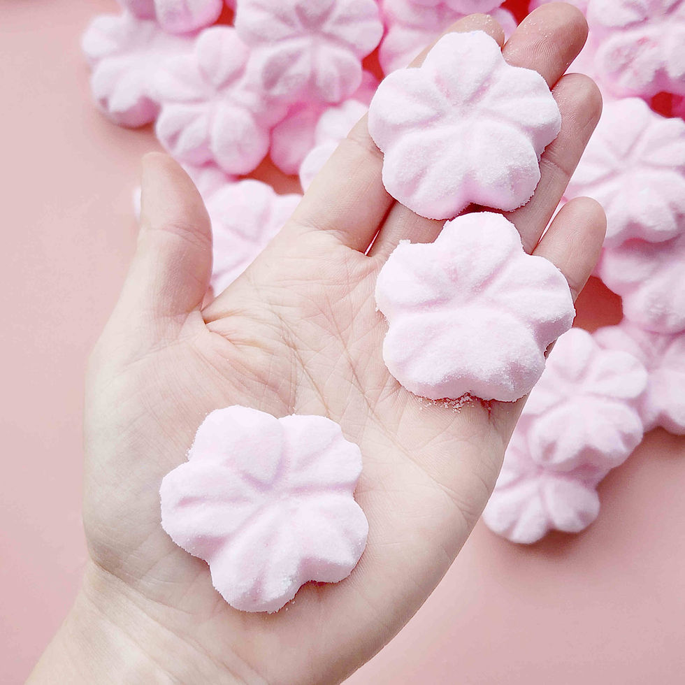 5 petal cherry blossom shaped bath bombs coloured light pink being held in a hand