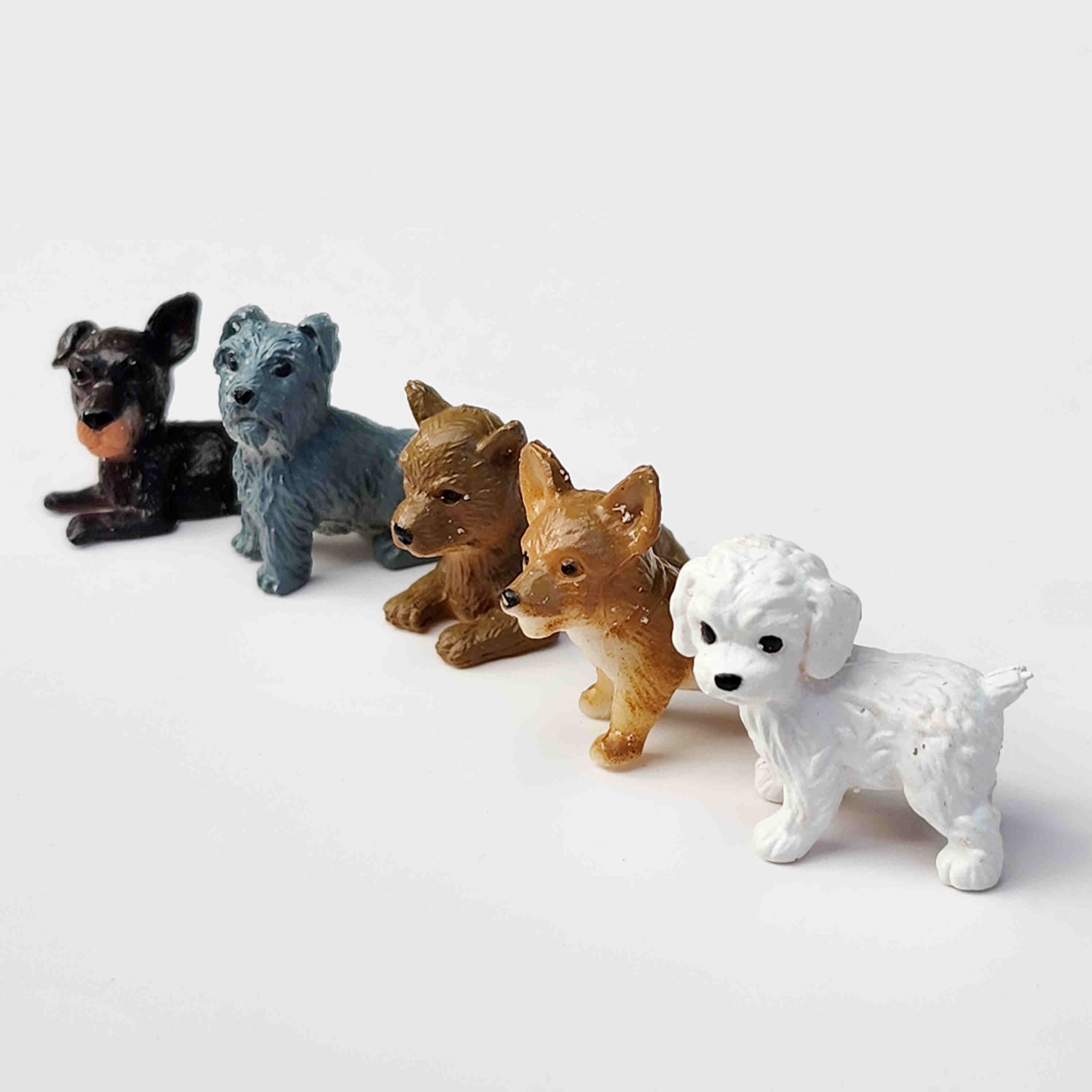 Row of puppy dog figurines lined up in a row on a white background