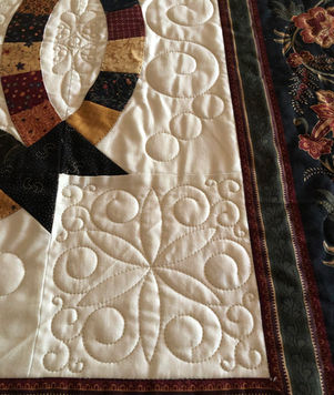 This double wedding ring quilt features custom quilting in a square with loops and swirls by Southern Quilts.