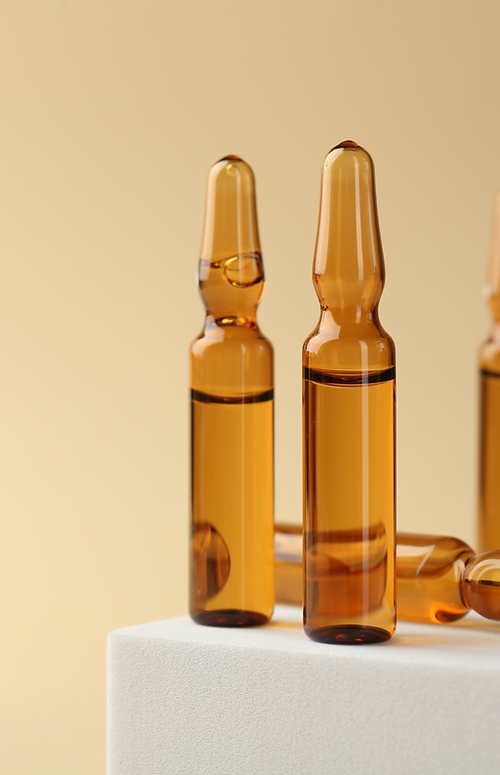 Glass ampoules with liquid on beige back