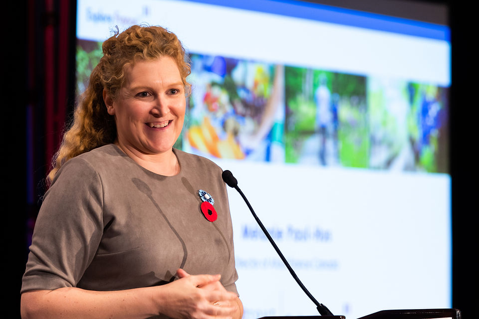 Lady speaking at a podium with a screen in the background