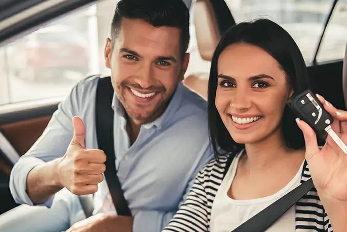 happy couple sat in car with car keys