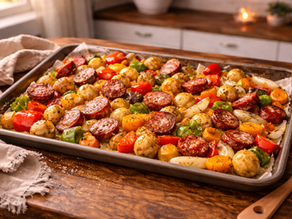 Roasted sheet pan sausage and vegetables served family style on a wooden table
