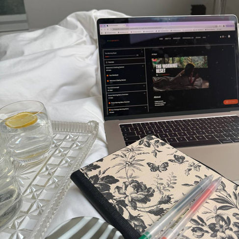 Structured morning routine with journaling notebook and laptop beside a woman preparing for work