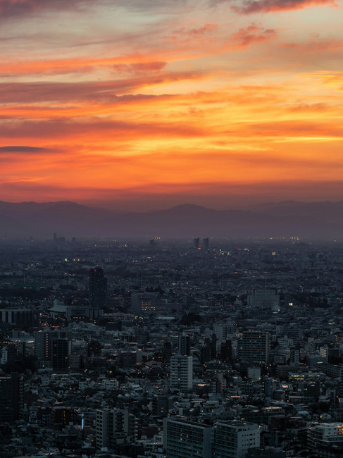 City skyline beneath a vibrant orange sunset, symbolising hope, perspective, and moving beyond recurring patterns of self-criticism with greater clarity and confidence.