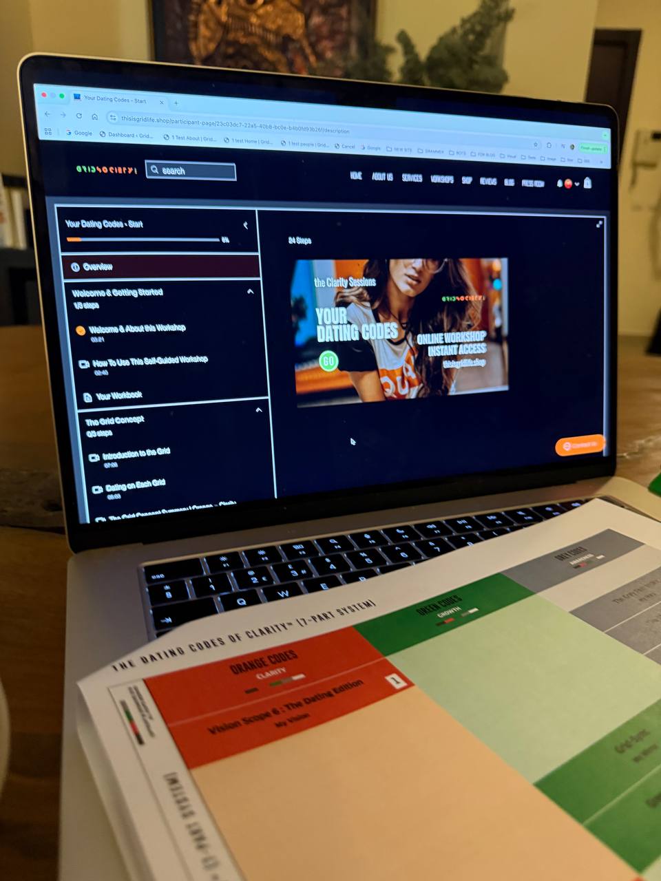 Laptop displaying the Grid Society Dating Codes Instant Access Workshop beside structured worksheets, symbolising fear-based hyper-criticism, emotional self-protection, and creating impossible standards in dating to avoid vulnerability or rejection.