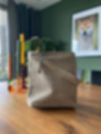 Beige suède tas op een houten tafel in een interieur.
