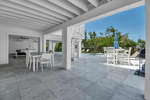 Modern covered patio with white dining furniture and spiral stairs.