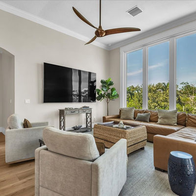 Modern living room with leather sectional and wood ceiling fan.