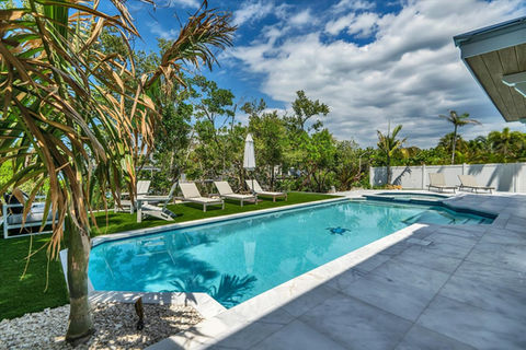 Backyard swimming pool with lounge chairs and palm trees
