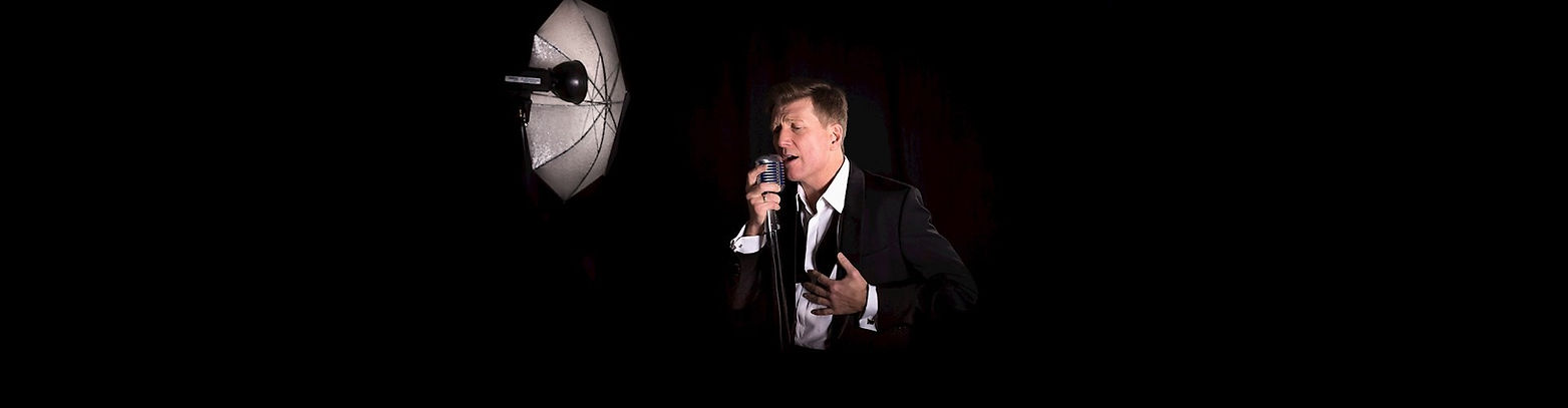 Zanger in pak zingt in microfoon tijdens een masterclass.