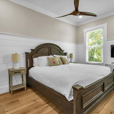 Modern bedroom with wood bed, shiplap walls, and ceiling fan